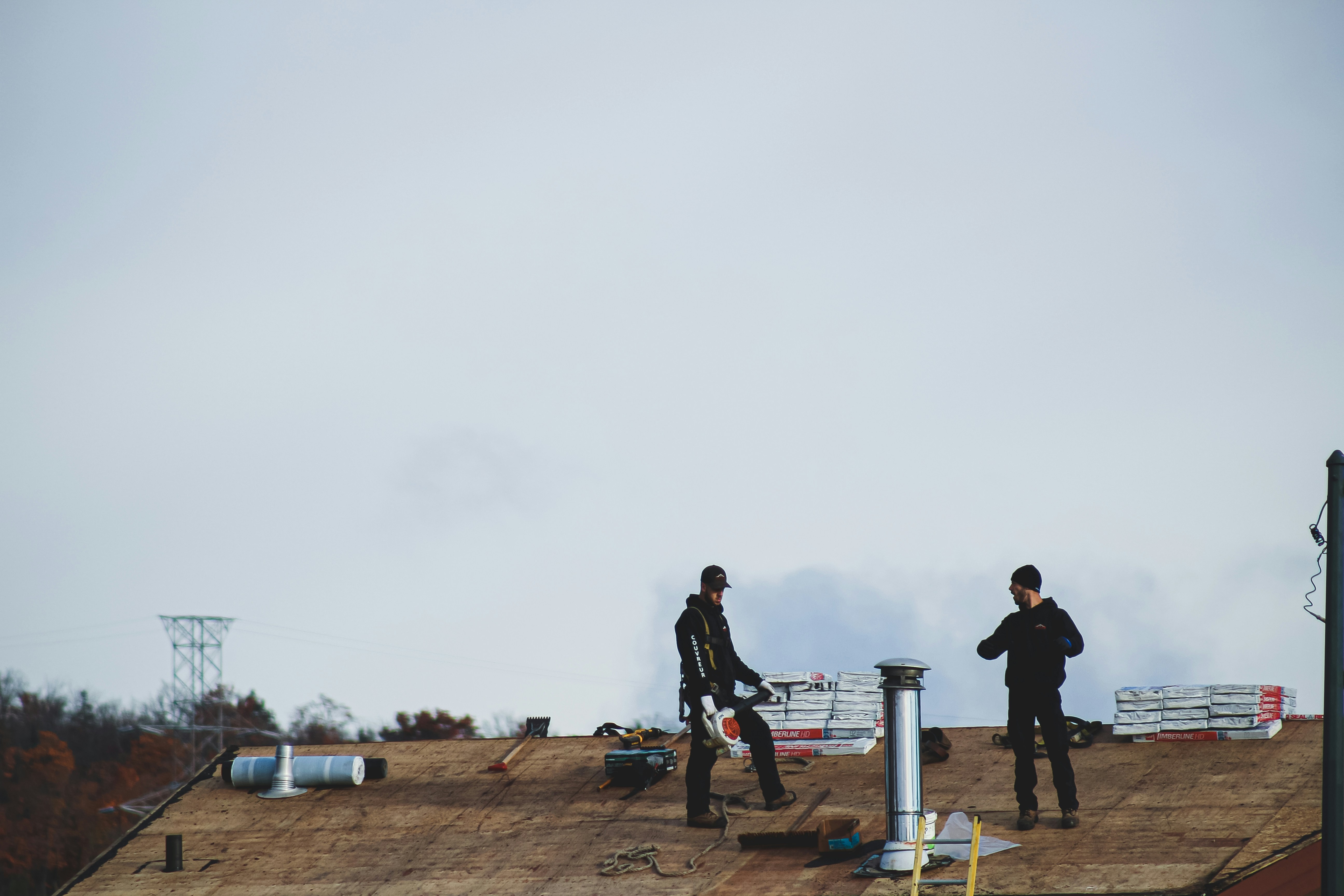 Two workers on a bare roof assessing their upcoming work